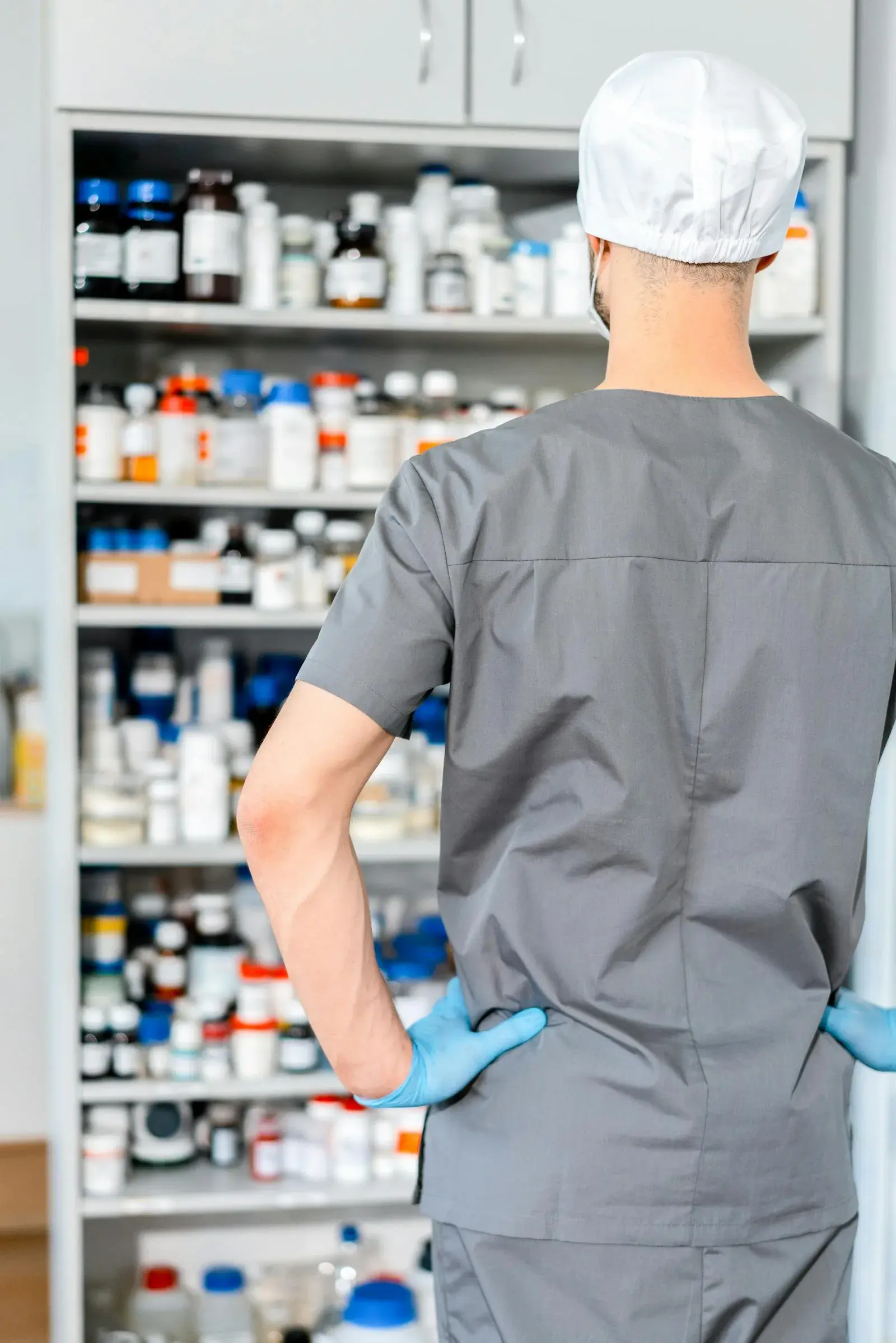 Pharmacist organizing medication shelves — illustrating the 2026 HCG shortage affecting men on TRT and the fertility preservation alternatives on pharmacy formularies